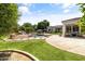 Beautifully landscaped backyard featuring a pool, rock features, lush lawn, and mature trees at 3410 E Inglewood Cir, Mesa, AZ 85213