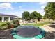 Expansive backyard featuring a trampoline, lush lawn, solar panels, pool with rock features and umbrellas at 3410 E Inglewood Cir, Mesa, AZ 85213