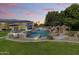 Gorgeous backyard oasis with a sparkling pool, rock waterfalls, lush landscaping, and an outdoor kitchen for entertaining at 3410 E Inglewood Cir, Mesa, AZ 85213
