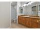 Bright bathroom with a large vanity, wood cabinets, tile floors and a shower/tub combination enclosed by a patterned curtain at 3410 E Inglewood Cir, Mesa, AZ 85213
