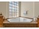 Soaking tub with glass block window and tile surround, flanked by cabinets and countertops at 3410 E Inglewood Cir, Mesa, AZ 85213
