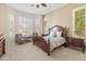 Comfortable bedroom featuring carpet flooring, a four-poster bed, sitting area and natural light from the large windows at 3410 E Inglewood Cir, Mesa, AZ 85213
