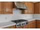 A kitchen with wooden cabinets, quartz countertops, and a stainless steel gas range and vent hood at 3410 E Inglewood Cir, Mesa, AZ 85213