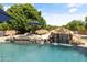 Stunning pool with a waterfall, rock features, lush landscaping, and a relaxing atmosphere at 3410 E Inglewood Cir, Mesa, AZ 85213