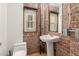 Charming bathroom with exposed brick walls, pedestal sink, toilet and window allowing natural light at 387 N 2Nd Ave # F2, Phoenix, AZ 85003