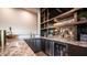 Custom bar featuring a granite countertop, wine fridge, sink, and decorative shelving with mirror backsplash at 4281 S Iowa St, Chandler, AZ 85248