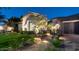 Well-lit home exterior with stone accents, a lush lawn, and manicured landscaping at twilight at 4281 S Iowa St, Chandler, AZ 85248