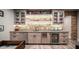 Charming wet bar with brick backsplash, glass-front cabinets, mini fridge, and under-cabinet lighting at 4281 S Iowa St, Chandler, AZ 85248
