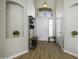Bright foyer featuring wood floors, hall tree, and decorative niches for plants and decor at 43283 W Hillman Dr, Maricopa, AZ 85138