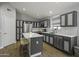 Bright, neutral kitchen features gray cabinets, an island with breakfast bar, stainless appliances, and tile backsplash at 43283 W Hillman Dr, Maricopa, AZ 85138