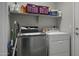A functional laundry room features a washer, dryer, and shelving for storage at 43283 W Hillman Dr, Maricopa, AZ 85138