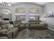 Open living room with seating for many, large windows, cathedral ceilings, and wood-look floors at 43283 W Hillman Dr, Maricopa, AZ 85138