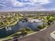 Aerial view of a community with a lake, pool, green spaces, and mountain views in the background at 43344 W Oster Dr, Maricopa, AZ 85138