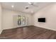 Bright living room featuring hardwood floors, neutral walls, ceiling fan, and TV at 43344 W Oster Dr, Maricopa, AZ 85138