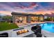 Stunning backyard at twilight with a pool, fire pit, and seamless indoor-outdoor living at 5033 N 205Th Gln, Buckeye, AZ 85396