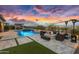 Backyard oasis with a pool, fire pit, and landscaped turf area, all bathed in the glow of sunset at 5033 N 205Th Gln, Buckeye, AZ 85396