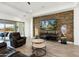 Cozy living room featuring a decorative stone wall, modern furniture, and ample natural light from the sliding glass door at 5033 N 205Th Gln, Buckeye, AZ 85396