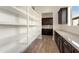 Walk-in pantry featuring white shelving, dark wood cabinets, and ample storage space at 5033 N 205Th Gln, Buckeye, AZ 85396