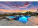 Backyard showcasing a pool and spa with LED lighting, complemented by a stunning sunset backdrop at 5033 N 205Th Gln, Buckeye, AZ 85396