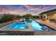 Serene backyard featuring a pool, spa, waterfall, and lush landscaping at dusk at 5033 N 205Th Gln, Buckeye, AZ 85396
