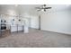 Bright open-concept living space with modern ceiling fan, carpeted area, and a view of the kitchen at 51942 W Sotol Rd, Maricopa, AZ 85139