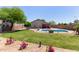 Beautiful backyard featuring an in-ground pool, green lawn, and covered patio space for relaxing at 6002 N 124Th Dr, Litchfield Park, AZ 85340