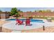 Relaxing backyard pool area with stylish red Adirondack chairs and ample space for outdoor entertaining at 6002 N 124Th Dr, Litchfield Park, AZ 85340