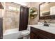 Bathroom with a shower-tub combo, wood vanity, and decorative shelving at 605 S Monterey St, Gilbert, AZ 85233