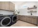 Well-equipped laundry room with a washer and dryer, upper and lower cabinets, and open shelving at 8549 E Indianola Ave, Scottsdale, AZ 85251