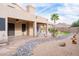 Inviting backyard featuring a covered patio, rock garden, and lush desert landscaping at 8635 W Country Gables Dr, Peoria, AZ 85381
