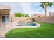 Backyard oasis boasts a sparkling pool, green artificial turf, and mature palm trees at 8635 W Country Gables Dr, Peoria, AZ 85381