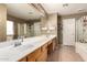 This primary bathroom features dual sinks with a large mirror, soaking tub and glass shower enclosure at 9343 W Quail Ave, Peoria, AZ 85382