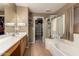 This primary bathroom features dual sinks, a glass shower enclosure, soaking tub and walk-in closet at 9343 W Quail Ave, Peoria, AZ 85382