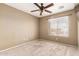 This bedroom features neutral walls, carpet flooring, a window bringing in plenty of natural light, and a ceiling fan at 9343 W Quail Ave, Peoria, AZ 85382