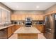 Functional kitchen with a central island, wooden cabinets, and modern stainless steel appliances at 9343 W Quail Ave, Peoria, AZ 85382