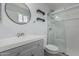 Bright bathroom features a glass-enclosed shower, toilet, and vanity with a round mirror at 9609 N 44Th Ave, Glendale, AZ 85302