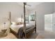 Comfortable bedroom with neutral paint, light carpet, a four-poster bed, and a view into the primary bathroom at 11331 E Cochise Dr, Scottsdale, AZ 85259