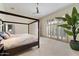 Spacious primary bedroom with a four-poster bed, neutral carpet, and large window allowing ample natural light at 11331 E Cochise Dr, Scottsdale, AZ 85259