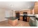Bright kitchen with wood cabinets and black appliances featuring a center island, and vinyl floors at 1203 E Bishop Dr, Tempe, AZ 85282