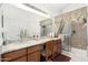 Bright bathroom features double sinks with a large mirror and a walk-in shower with a patterned curtain at 16083 W Cambridge Ave, Goodyear, AZ 85395