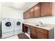 Functional laundry room featuring a washer and dryer with built-in cabinets and countertop space at 16083 W Cambridge Ave, Goodyear, AZ 85395