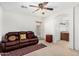 Cozy living room with comfortable leather sofa, ceiling fan, and easy access to other rooms at 16083 W Cambridge Ave, Goodyear, AZ 85395