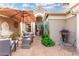 A cozy outdoor patio with comfortable seating under an umbrella, lush greenery, and a welcoming entrance at 16083 W Cambridge Ave, Goodyear, AZ 85395
