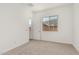 A simple bedroom featuring neutral carpet, white walls, and a large window at 16494 W Creedance Blvd, Surprise, AZ 85387