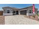 Charming home exterior with a paver driveway, a two-car garage, and desert landscaping at 16494 W Creedance Blvd, Surprise, AZ 85387