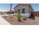 Home exterior with desert landscaping, including a tree and scattered vegetation, offering a low-maintenance yard at 16494 W Creedance Blvd, Surprise, AZ 85387