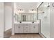 Modern bathroom featuring a double sink vanity, large mirror, and glass-enclosed shower with black trim at 16550 W Creedance Blvd, Surprise, AZ 85387