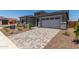 Paver driveway leading to a two-car garage, framed by a beautifully landscaped yard with stone accents at 16550 W Creedance Blvd, Surprise, AZ 85387