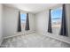 Empty bedroom with plush carpet, two windows, and neutral gray walls at 16840 W Monroe St, Goodyear, AZ 85338