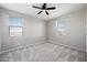 Clean, empty bedroom features soft carpeting, two sunny windows, and neutral gray walls at 16840 W Monroe St, Goodyear, AZ 85338